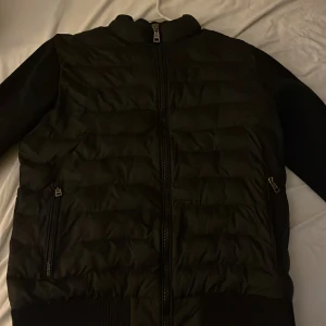 Svart dunjacka från Moncler - Säljer en snygg svart dunjacka från Moncler. Jackan har en quiltad design med dragkedja framtill och två praktiska fickor med dragkedjor. Perfekt för kyliga dagar och håller dig varm och stilren. Passar både till vardags och lite finare tillfällen. 🖤 Passar S/M.       PRISET GÅR ATT DISKUTERA!