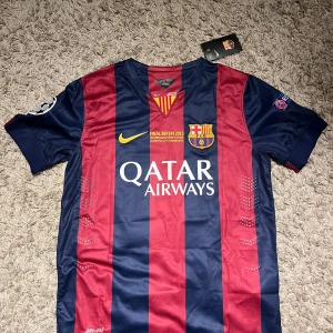  FC Barcelona fotbollströja 14/15 - Säljer en FC Barcelona fotbollströja i blårött med Neymar Jr och nummer 11 på ryggen. Tröjan har korta ärmar och är i oanvänt skick. Perfekt för fans av Barca och Neymar! (Obs ej original!