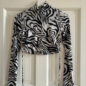 Topp från Nelly - Croppad långärmad topp från Nelly med öppen rygg. Snörning som knyts i ryggen, använd vid fåtal tillfällen 