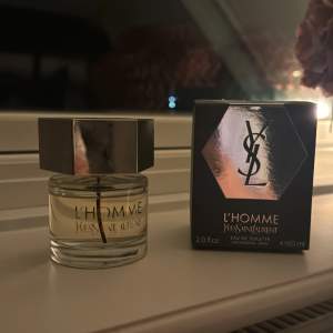 Säljer en elegant och maskulin L'Homme Eau de Toilette från Yves Saint Laurent. Flaskan är stilren med en sexkantig metallkork och rymmer 60 ml. Perfekt för den som vill ha en sofistikerad doft som passar både dag och natt. Kommer i originalförpackning.