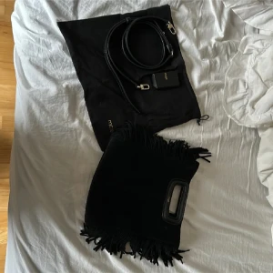 Maje väska  - Säljer en snygg svart maje väska med fransar. Den har en stilren design med ett handtag och en avtagbar axelrem. Perfekt för både vardag och fest! Väskan är i mycket bra skick och kommer med en skyddspåse och kvitto. Knappt andvänd!!🥰💖🥹