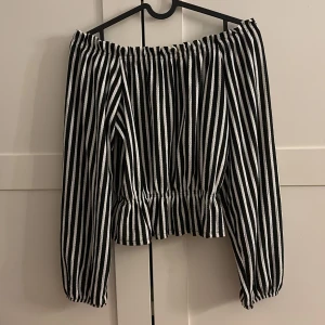Randig offshoulder topp - Säljer en superfin svartvit randig offshoulder topp. Den har långa armar och en elastisk kant vid axlarna för en bekväm passform. Perfekt för både vardag och fest! 🖤🤍