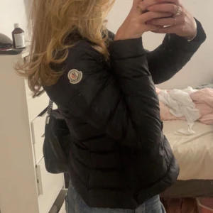 Svart dunjacka från Moncler - Säljer en snygg svart dunjacka från Moncler i mycket bra skick. tight passform och långa ärmar. Monclers logga på ärmen. Supermysig och stilren 