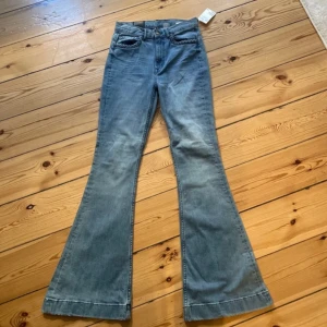 Blå bootcut jeans från H&M - Säljer ett par snygga blå bootcut jeans från H&M. De har en flätad detalj vid fickorna och är i nytt skick med prislappen kvar. Perfekta för en avslappnad men stilren look. Passar bra till både vardag och fest!