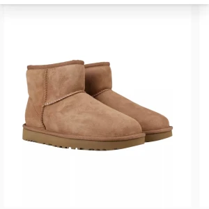 Bruna UGG Classic Mini II - Säljer ett par bruna UGG Classic Mini II boots i storlek 36. De är gjorda av mjuk mocka och har en varm, fluffig insida som är perfekt för kalla dagar. Skorna är helt oanvända och säljer då dom är för små. Perfekta för höst och vinter!