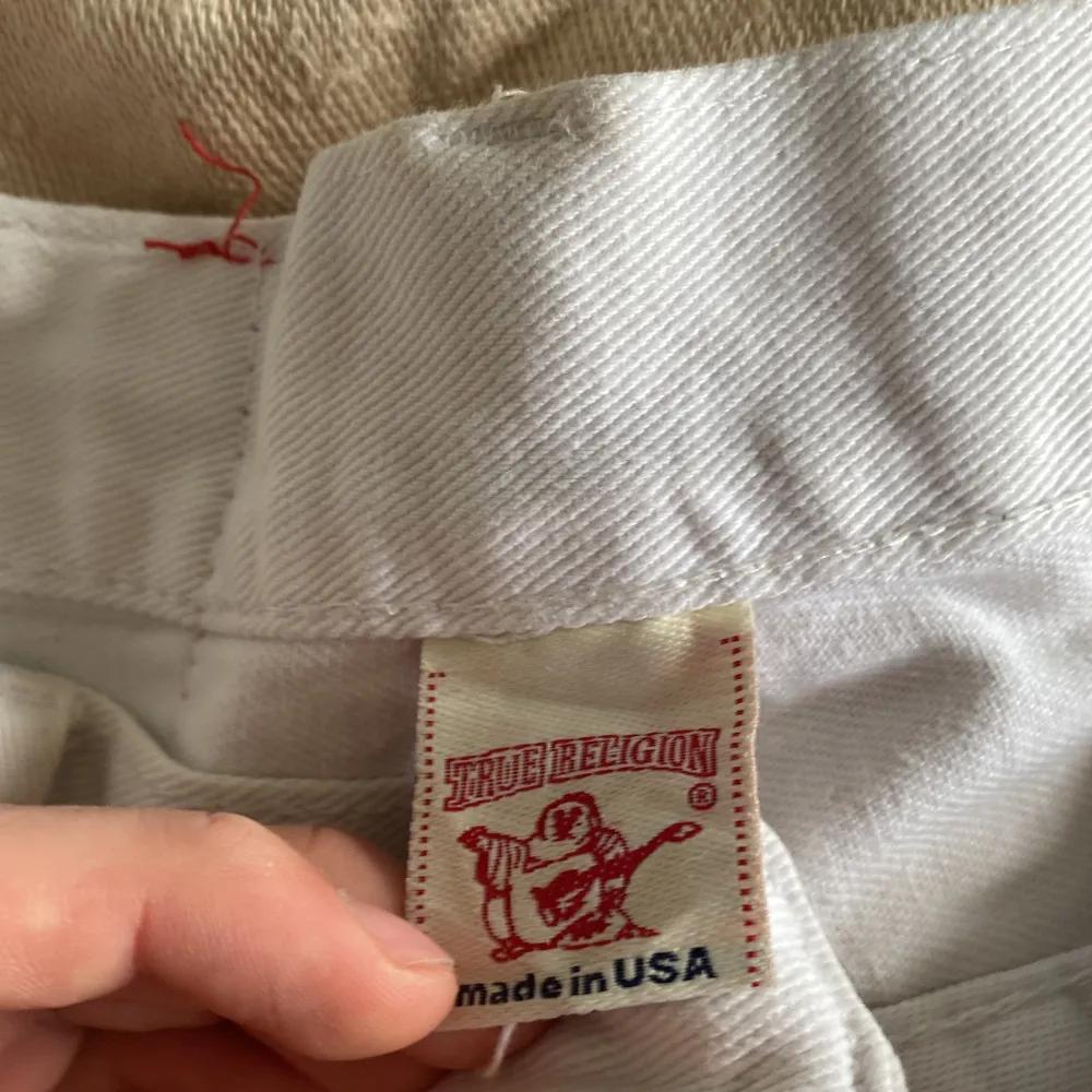 Säljer ett par vita jeans från True Religion i bra skick. De har en klassisk femficksdesign med snygga detaljer på bakfickorna. Jeansen är tillverkade i USA och har en normal passform. Perfekta för både vardag och fest. Saknar knapp vilket lätt kan sys på. . Jeans & Byxor.