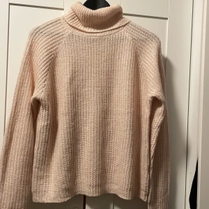 Beige stickad polotröja - Säljer en supermysig babyrosa stickad polotröja. Den har en hög krage som håller dig varm under kalla dagar. Tröjan är långärmad och perfekt för höst och vinter. Den är i nyskick och passar perfekt för en avslappnad och stilren look.