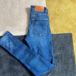 Blå jeans med skinny passform - Säljer ett par snygga blå jeans med slim passform. De har en klassisk femficksdesign och en läderpatch baktill. Perfekta för både vardag och fest! Ny pris 1500kr💸