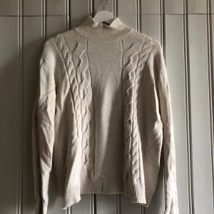 Beige stickad tröja med flätmönster - Säljer en supermysig beige stickad tröja med ett snyggt flätmönster på framsidan. Tröjan har långa ärmar och en liten krage. Perfekt för höst och vinter! Står ingen storlek men passar mig som brukar ha S eller M 🥰