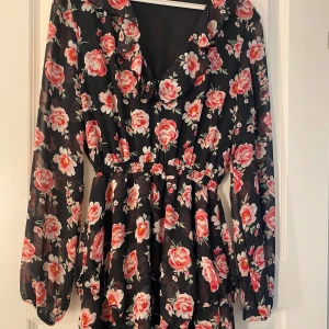 Långärmad klänning  - Svart med rosa blommor lite volanger 