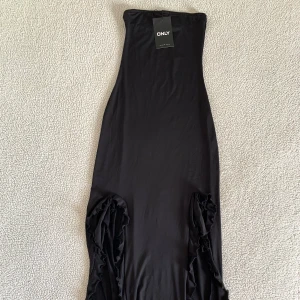 Only svart midiklänning med volanger - Otroligt snygg bandeau klänning med volanger från Only. Håller sig på plats med silikonremsa vid bysten. Stretchigt material. Sitter som ett smäck. 💃 Ny med prislappar, utan anmärkningar. Ordinariepris 459kr.