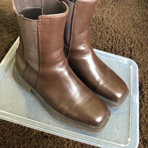 Bruna boots  - Snygga boots i brunt med kvadratisk tå och höga i anklarna. Säljer pga att jag har andra vinter/höst skor som används mer.  Köpta förra vintern men använda ca 5 ggr. På kanten av sulorna är det lite skavanker, men ingenting som syns. Från DinSko.  