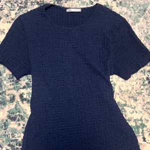 Mörkblå klänning från Zara - Säljer en superfin mörkblå top från Zara. Den har en cool textur och korta ärmar, perfekt för både vardag och fest.