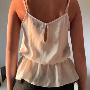 Sött, vitt linne - En söt vit topp från Bikbok med smala axelband och volanger på både upptill och nedtill. Storlek S.
