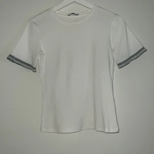 Vit zara t-shirt med strass - Superfin vit t-shirt med strass i ärmarna perfekt om man vill ha en lite roligare t-shirt köpt från zara för ca 300 säljer då den inte kommer till användning 