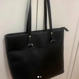Svart väska - Fin rymlig väska passar bra till skolan!💕den är 32 cm på längden och 27cm på höjden. Använts lite men i väldigt bra skick! Har dragkedja ifall man vill stänga den där uppe