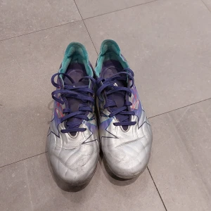 Adidas copa champions league edition - Säljer ett par copa fotbollsskor från Adidas. De har en snygg design med lila och turkosa detaljer samt snörning och även champions league stjärnor. Perfekta för fotbollsträningen eller matchen! Skorna är i bra skick och redo för nya äventyr på planen. Dem är använda och lite paj här och där men fungerar fortfarande bra. Nypris 3200kr 