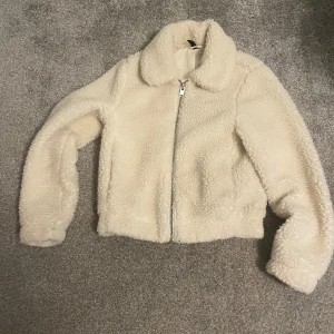 Vit teddyjacka - Mysig vit teddyjacka i mycket bra skick. Perfekt för höst och vinter med dragkedja framtill. Jackan har en normal passform och långa ärmar. Den är supermjuk och håller dig varm under kyliga dagar. Ett måste för garderoben! Den säljs pga att jag inte använder den längre💗