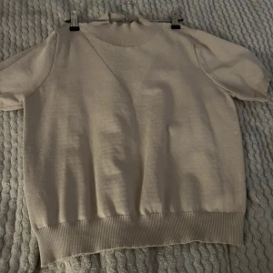 Beige kortärmad tröja - Säljer en beige tröja med korta ärmar. Perfekt för vår och sommar, gjord i ett mjukt material som känns skönt mot huden. Passar både till vardags och lite finare tillfällen.