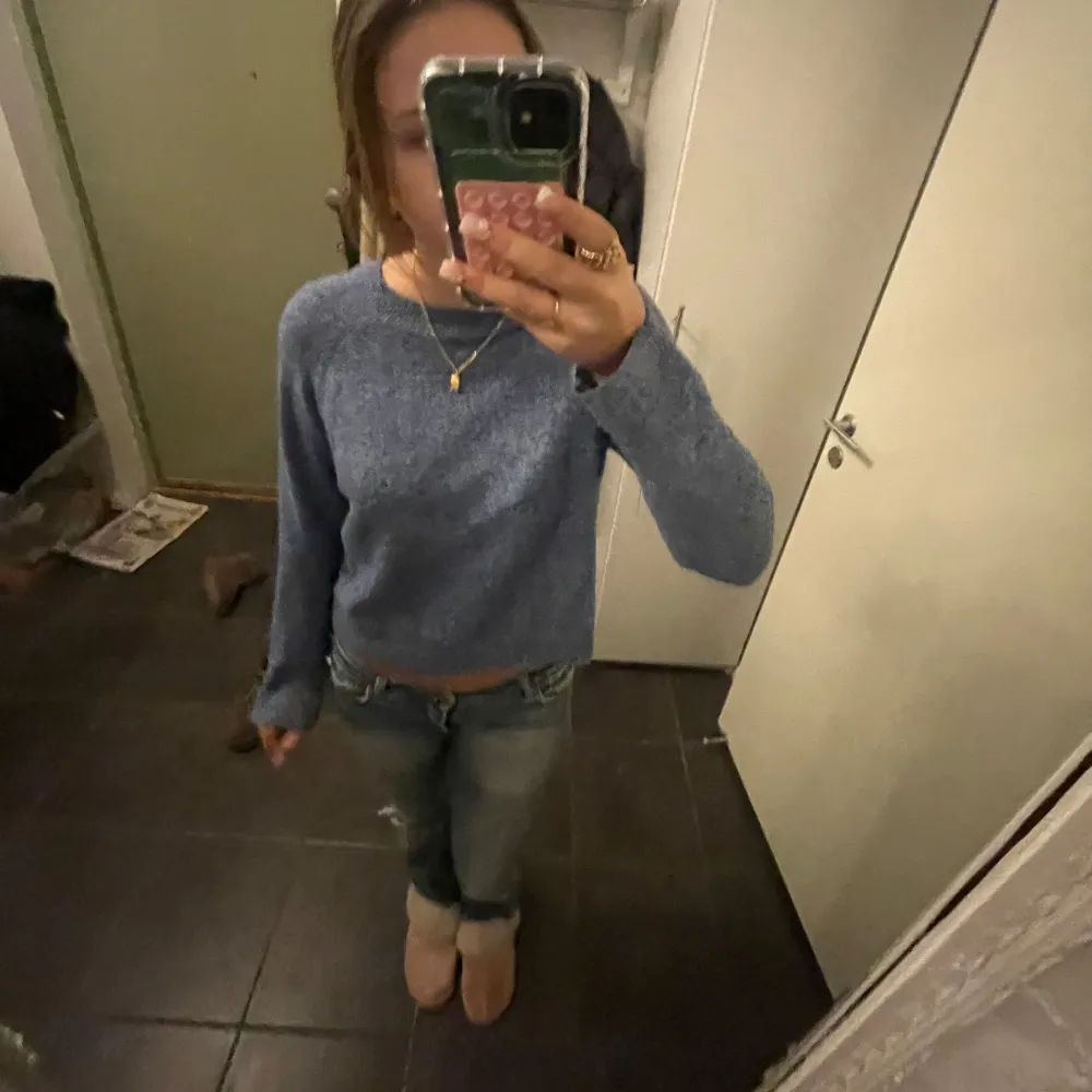 Säljer en snygg blå stickad tröja med lång ärm. Tröjan har en enkel design och är perfekt för kyligare dagar. Den är bekväm och lätt att matcha med olika outfits. Har rivits upp lite i sömmen nästan längst ner på armen, inget man märker av dock. Neuletakit & Villapaidat.