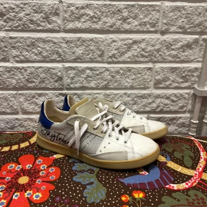 Hdnander sneakers - Snygga vita sneakers från Hdnander med blå detaljer och snörning. Skorna har en klassisk design med stjärnmönster på sidan och texten 'Hide Dreams' på hälen. Tillverkade i Italien på ett nypris av 490 Euro. Kvitto finns