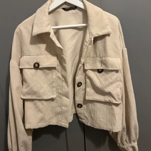 Beige manchesterjacka  - Snygg beige manchesterjacka från Shein med stora fickor och knappar framtill. Jackan har en croppad design och långa ärmar