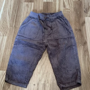 Bruna randiga byxor från Zara - Säljer ett par bruna randiga byxor från Zara för barn i storlek 12-18 månader. Byxorna har en bekväm passform med elastisk midja och snörning. Perfekta för både lek och mysiga dagar.