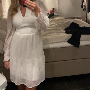 Vit klänning med lång ärm - Elegant vit klänning med långärmad design och v-ringad hals från Veromoda. Perfekt till student eller skol avslutning. Går att dra åt i midjan så den passar bättre.