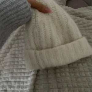 Vit stickad mössa - Mysig vit stickad mössa perfekt för kyliga dagar. Den har en ribbad design som ger extra stil och värme. Passar utmärkt för både höst och vinter. Material alpacka och ull! 