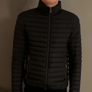 Svart Colmar lightweight down jacka - Säljer en snygg svart dunjacka från Colmar i bra skick. Perfekt för höst och vår. Den är storlek 48 vilket skulle passa någon som brukar ha S-M. Det ända tecknet på användning är att bokstäverna på loggan är lite slitna i botten vilket man ser på sista bilden. Den har även qr kod. Hör av dig vi intresse! 