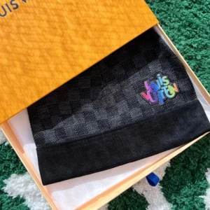 Lv mössa - Snygg svart mössa från Louis Vuitton med ett diskret rutmönster och färgglad broderad logga. Perfekt för att hålla sig varm och stilren under kyliga dagar. Kommer i originalförpackning.