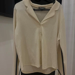 Beige långärmad blus från Missguided - Elegant beige blus från Missguided med långa ärmar och knappar framtill.