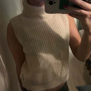 Offwhite stickad polotröja - Säljer en superfin offwhite stickad polotröja utan ärmar från designbysi. Perfekt för lager-på-lager under hösten eller vintern. Den är mjuk och bekväm med en hög polokrage som håller dig varm. Är även kort i modellen men väldigt stilren o snygg💖