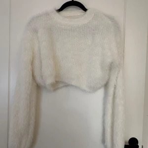 Vit fluffig croppad tröja - Supermysig vit fluffig tröja som är croppad och perfekt för kyliga dagar. Den har långa ärmar och är gjord i ett mjukt material som känns som en kram. Perfekt för att mysa hemma eller för en avslappnad dag ute. 🧡