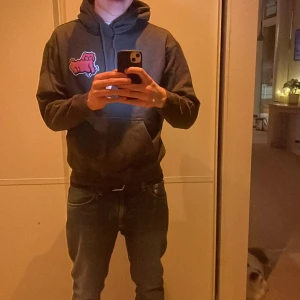 Svart hoodie från Weekday - Säljer en svart hoodie från Weekday med en cool rosa grafik på bröstet. Perfekt för en avslappnad stil med sin bekväma passform och klassiska design. Hör av dig vid intresse! Säljer då den börjar blir för liten passar 100% Small också.