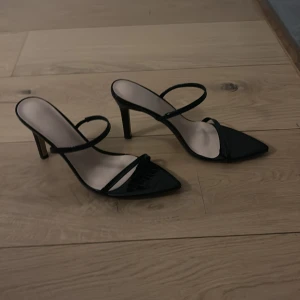Svarta klackskor med spetsig tå - Eleganta svarta klackskor med spetsig tå och dubbla remmar. Perfekta för en stilren look.