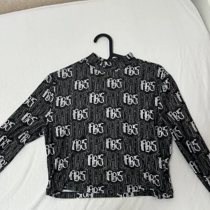 Svart och vit mönstrad topp från FB Sister - Säljer en cool svart och vit långärmad topp från FB Sister i storlek M. Den har ett unikt mönster med text över hela tyget och en croppad passform. Perfekt för en avslappnad stil eller en utekväll. Toppen är i mycket bra skick och redo för nya äventyr!