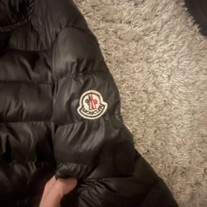 Svart dunjacka från Moncler - Snygg svart dunjacka från Moncler med dragkedja och quiltad design. Perfekt för kyligare väder med sin stilrena look och varma material. Skriv om ni undrar nått mer💕