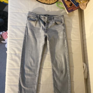 Grå jeans från Jack & Jones - Säljer ett par snygga grå jeans från Jack & Jones. De har en klassisk femficksdesign och är i väldigt bra skick. Perfekta för både vardag och fest! Passformen är straight och de har en knappgylf. Bälte ingår för 100kr extra.