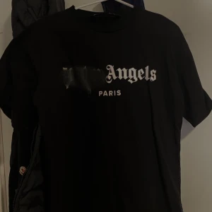 Svart t-shirt med tryck - Snygg svart t-shirt från Palm Angels med tryck i vitt. Perfekt för en stilren look med en touch av streetwear. T-shirten har korta ärmar och en normal passform.