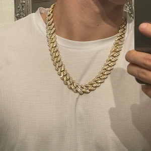 Guldglittrigt halsband - Säljer ett snyggt och glittrigt halsband i guld. Perfekt för att lyfta vilken outfit som helst med lite extra bling. Halsbandet har en chunky design med stora länkar som är täckta av glittrande stenar. Passar perfekt för festliga tillfällen eller när du bara vill känna dig extra glamorös. 🥳✨