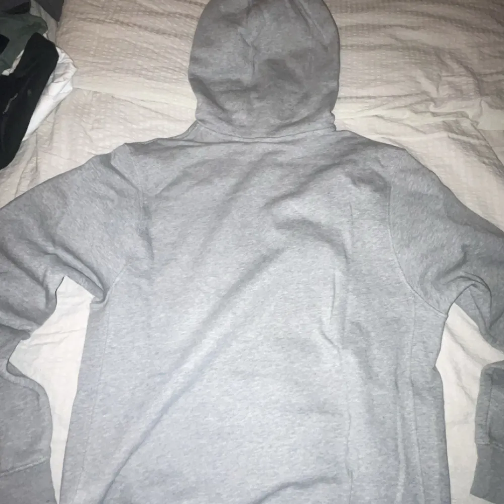 Säljer en grå hoodie från Nike i storlek S. Den har en klassisk design med en blå Nike-logga på bröstet och en stor ficka framtill. Perfekt för både träning och vardag. Huvan har dragsko för justering. Superbekväm och stilren! Har används ett par gånger och har ej gått sönder eller är ej sliten. S passar M!!. Tröjor & Koftor.