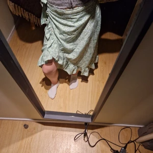 Grön blommig kjol från Vero Moda - Säljer en superfin grön blommig kjol från Vero Moda. Den har en omlott-design med volangdetaljer och knytning i midjan. Perfekt för vår och sommar! 🌸