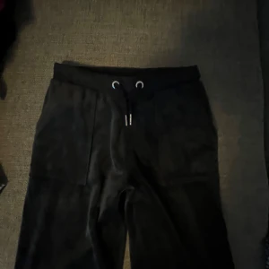 Marin blåa mjukisbyxor från Juicy Couture - (Stor storlek)Säljer ett par marin blåa mjukisbyxor från Juicy Couture. De är supermjuka och har en broderad logga på benet. Byxorna har snörning i midjan och praktiska fickor med knappar bak. Perfekta för en chill dag hemma eller en avslappnad utflykt.