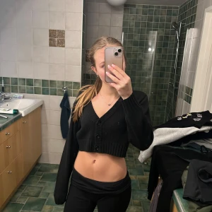 Svart croppad kofta från H&M  - Säljer en svart croppad kofta från H&M  i storlek XS. Den är stickad och har en v-ringad design med knappar framtill. Perfekt för höst och vår, och funkar både till vardags och fest. Superfin och i bra skick!