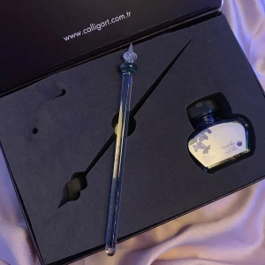 Elegant Bläckset med Personligt Designad Glaspenna - Säljer ett paket bestående av en burk blått bläck och en vacker, personligt designad glaspenna. Doppa spetsen i bläcket och rulla den lätt på sidorna för att få en perfekt bläckdosering. Denna penna ger en unik och stilfull skrivupplevelse på vanligt papper. Perfekt som födelsedagspresent eller gåva till någon som uppskattar vackra skrivverktyg. Inköpt i Turkiet.