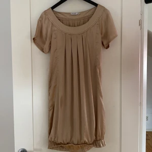 Champagne färgad klänning - Snygg champagne färgad klänning, passar både till sommaren men också nu på vintern! Fint matrial. klänningen är från märket Vila och är i storlek XS