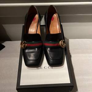 Säljer ett par eleganta svarta loafers från Gucci, model Marmont i skinn med en stilren mellanhög klack (7 cm)  Skorna har det ikoniska gröna och röda bandet med Guccis klassiska dubbel G framtill. Perfekta för både vardag och fest! 🖤