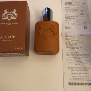 Parfums de Marly Althaïr Eau de Parfum - Säljer en lyxig Althaïr Eau de Parfum från Parfums de Marly. Flaskan är brun med en elegant silverfärgad kork och har en kapacitet på 75 ml. Förpackningen är stilren och matchar flaskans design. Perfekt för den som vill ha en sofistikerad doft med en touch av exklusivitet. Endast använd för extern bruk. Aldrig använd!!!!!!!!!