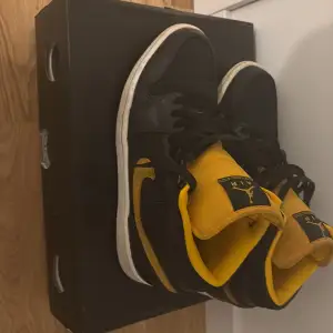 Säljer ett par snygga Nike Air Jordans i svart och gult. Skorna är i bra skick och har den klassiska Air Jordan-loggan på plösen. Storlek 42 och sparsamt använda. Exk Box